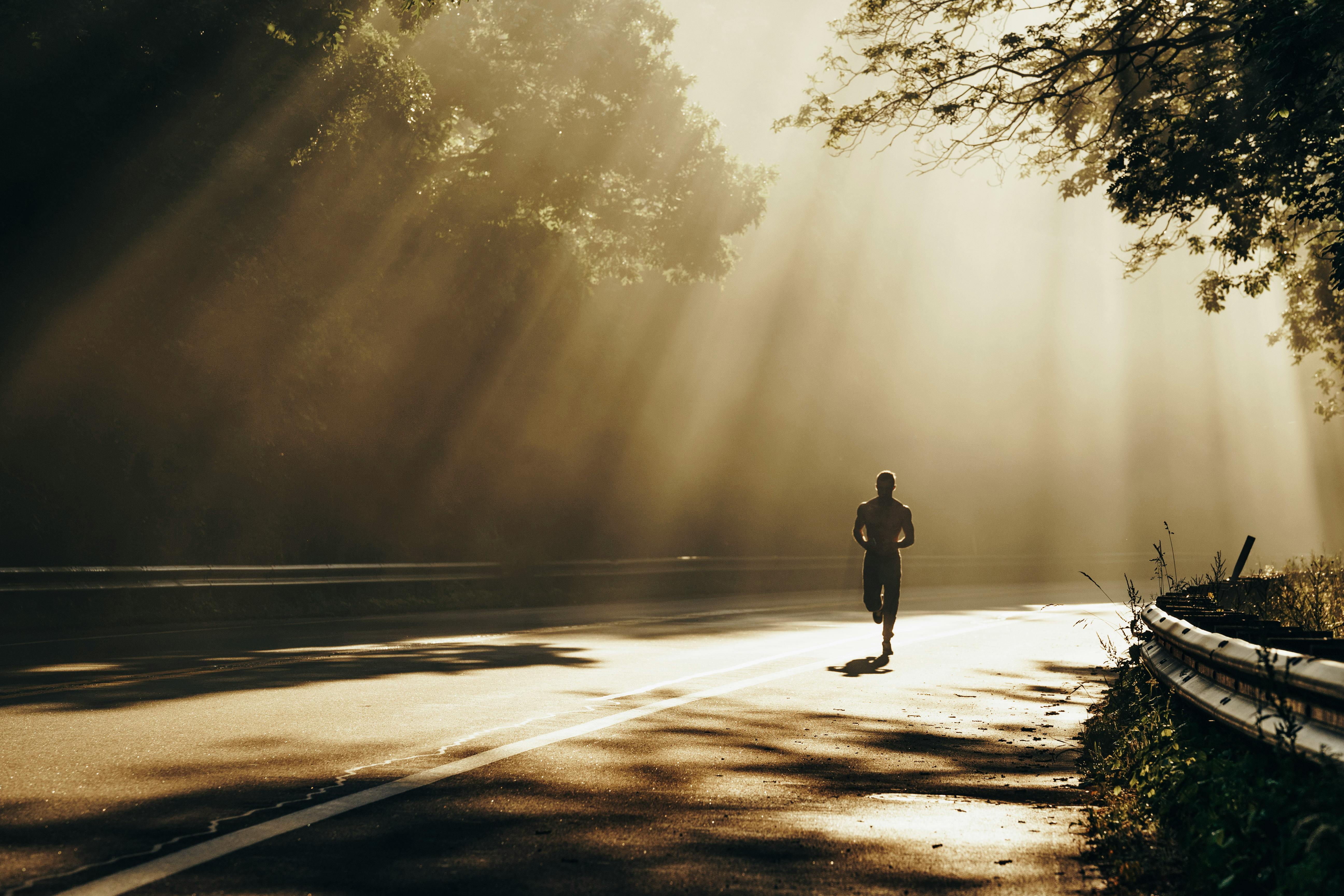 Runner training alone on a quiet road at sunrise